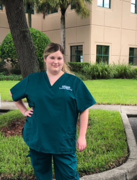 student standing in front of Keiser University campus