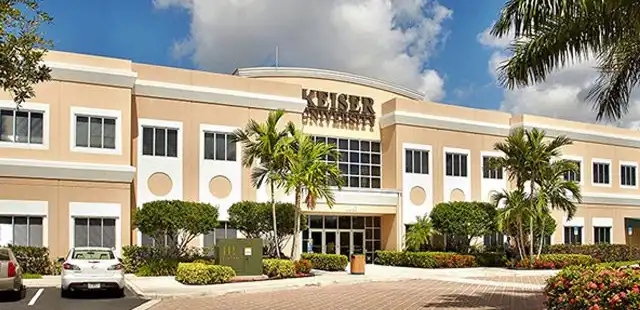Front entrance of a large office building at Keiser University campus, featuring modern architecture and glass doors.
