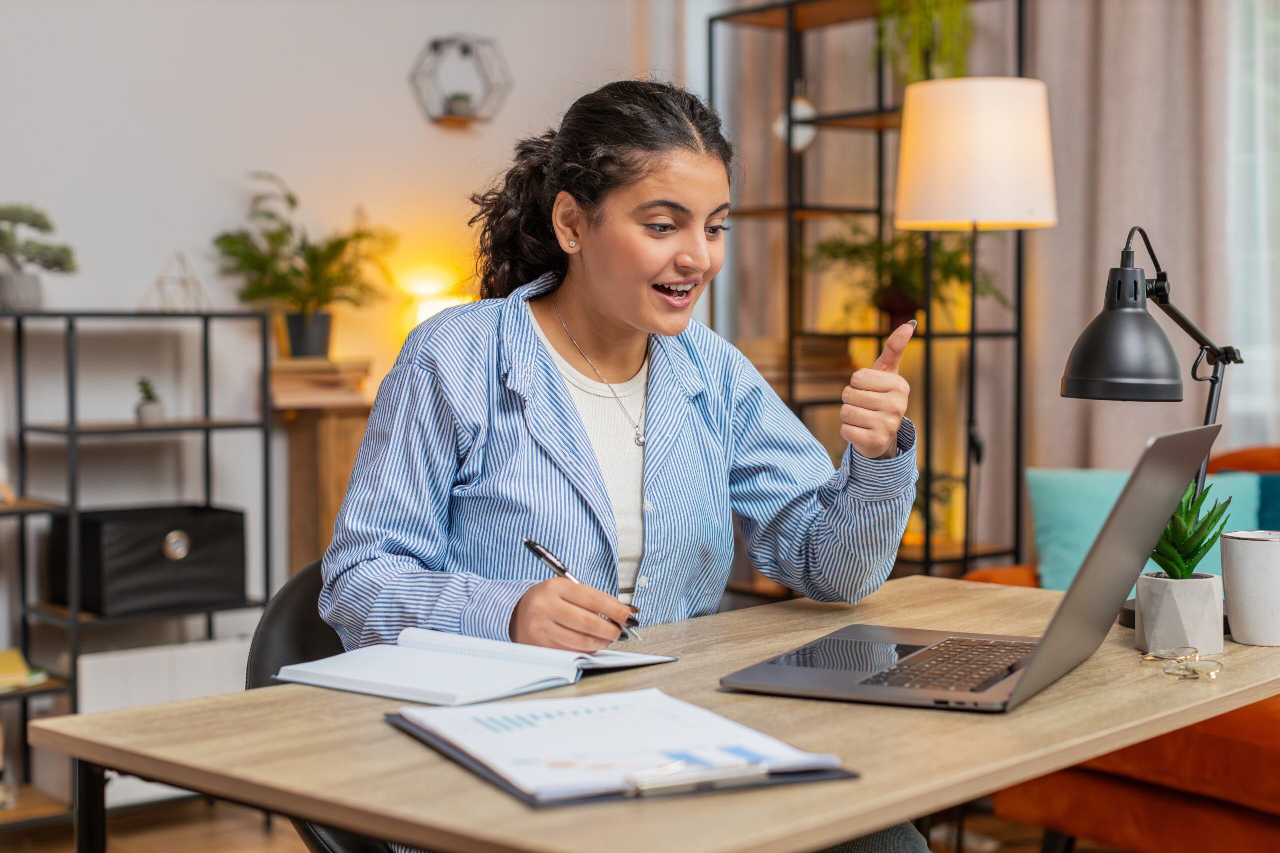 Female university student in a denim jacket using a laptop in a classroom setting.