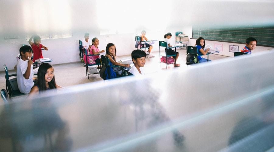 A group of students sitting at desks, engaged in learning activities in a bright classroom setting.